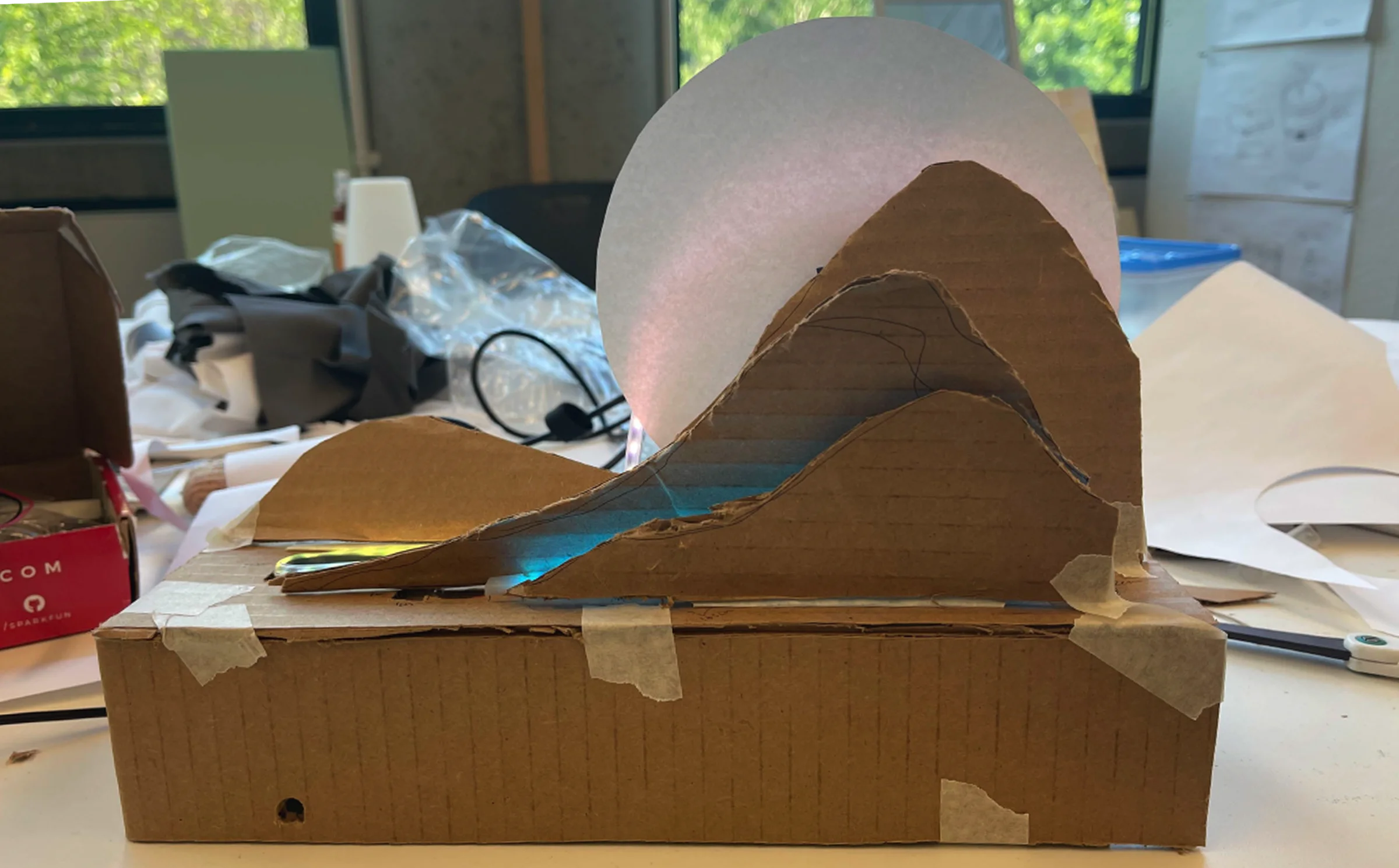 Fully assembled cardboard model — sun, landscape, and base